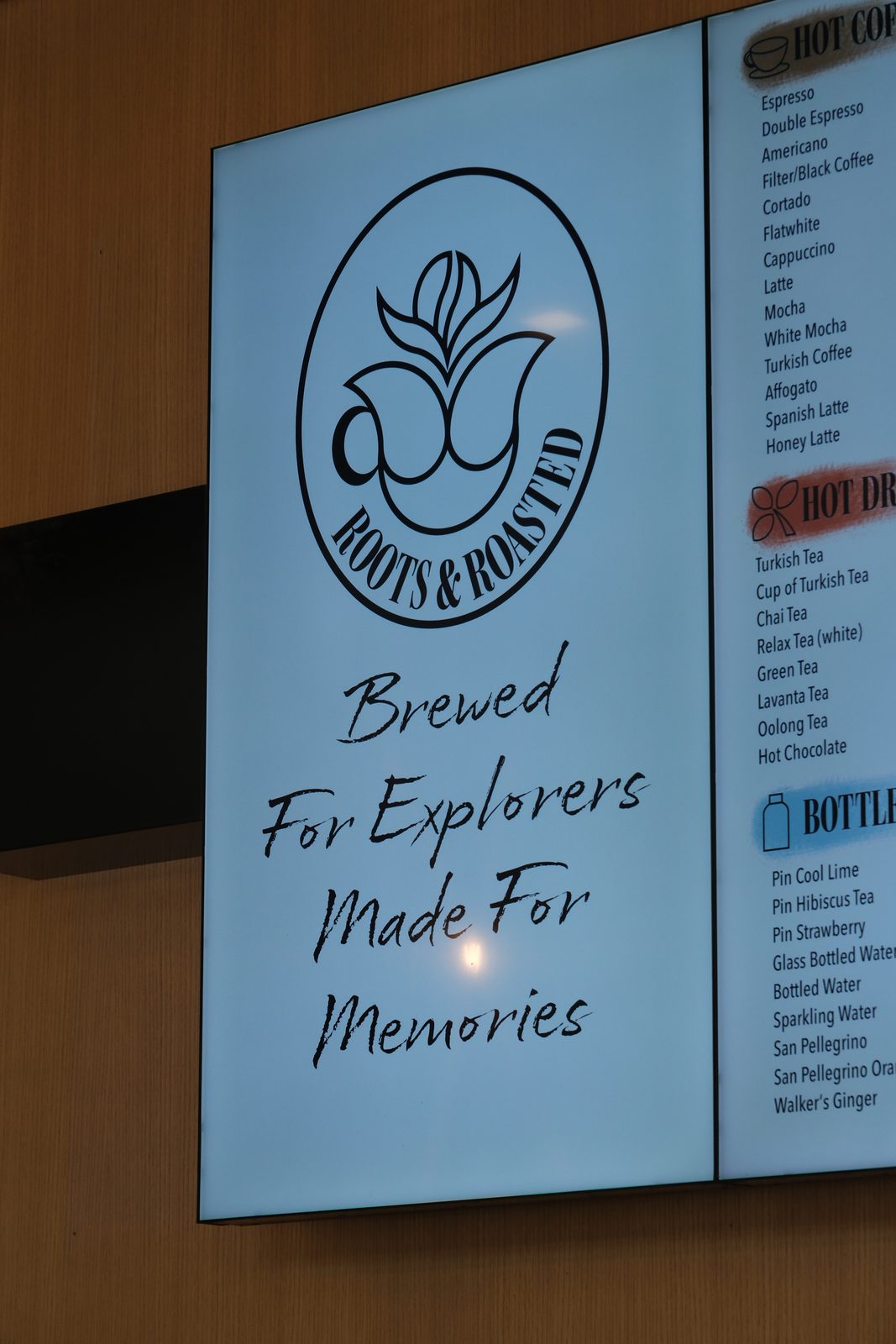 Menu board with the Roots & Roasted logo and the words “Brewed For Explorers, Made For Memories”